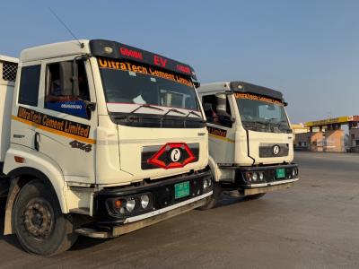 A couple of trucks stand together on a tarred road